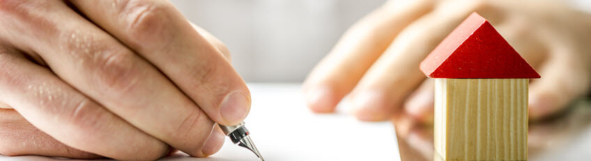 Photo of a person writing and a model house